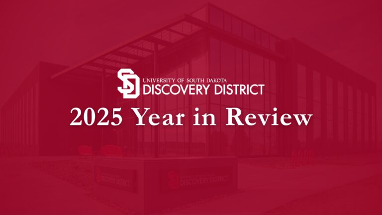 USD Discovery District logo over title, "2025 Year in Review" over dark red gradient image of Building 1