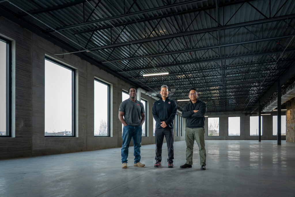 Marc-Antoine Niamba, Ryan Oines, and Tung Nguyen standing inside the unfinished core and shell of Building 1 at the USD Discovery District, showing the progress of the new bioscience facility.