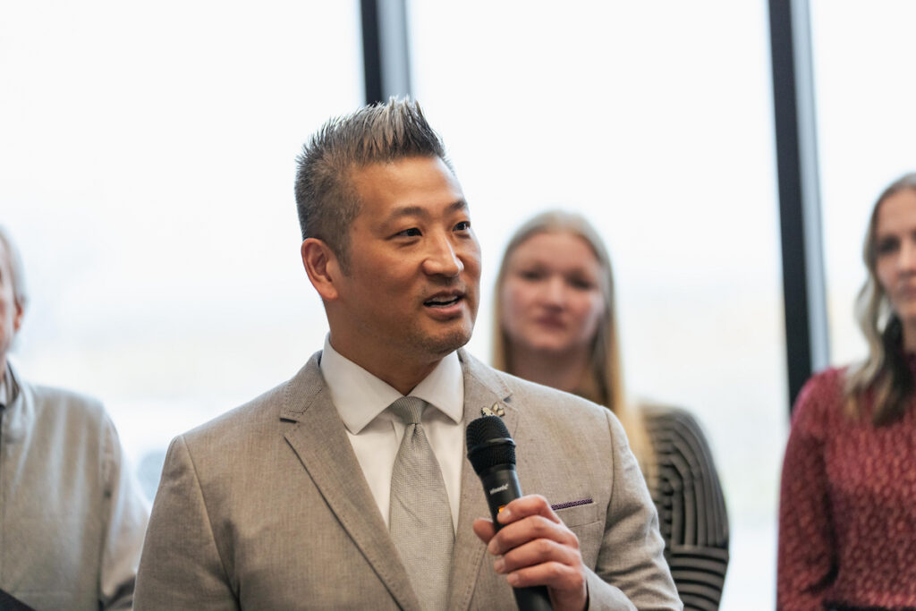 Ryan Oines, president of the USD Discovery District, speaks into a microphone during the Grand Opening event, addressing guests about the District’s growing impact on research and innovation.