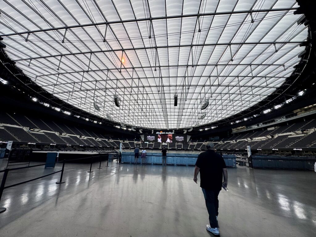 Man walks into Allegiant Stadium, a large capital project completed in 31-month building schedule. 